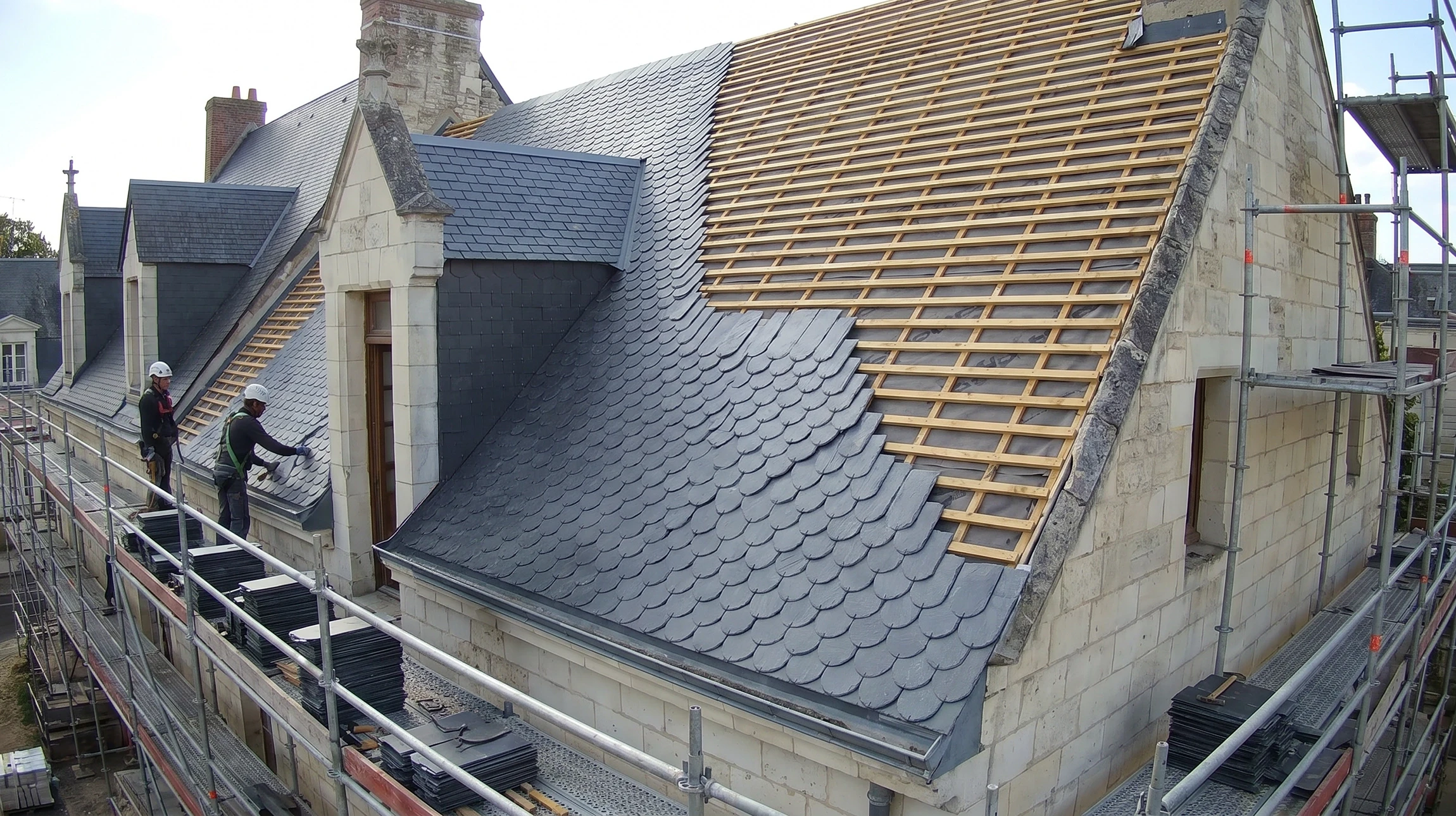 Photographier un couvreur professionnel en train de poser des bardeaux d'ardoise naturelle sur une pente de toiture. La scène doit montrer clairement la technique d'installation des ardoises, les outils du métier, et l'environnement réel d'un chantier de rénovation de toiture sur une résidence. L'angle doit mettre en avant la texture et la couleur des ardoises, ainsi que le travail artisanal de précision. Lumière naturelle de jour, perspective montrant tant l'artisan que les matériaux utilisés.