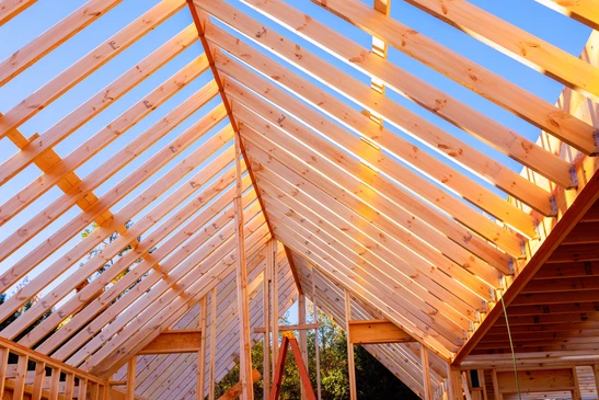 Charpente traditionnelle en bois massif vue de dessous, montrant l'assemblage complexe de poutres principales et secondaires